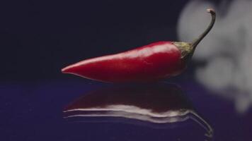 Close-up of hot pepper with smoke. Stock footage. Red chili pepper on isolated background with smoke. Hot pepper shrouds in thick fog. Spectacular chili pepper in thick smoke video