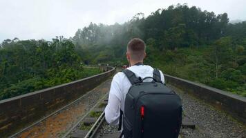 posteriore Visualizza di un' uomo turista assunzione immagini di montagna foreste paesaggio su smartphone. azione. escursionista a piedi su linee ferroviarie. video