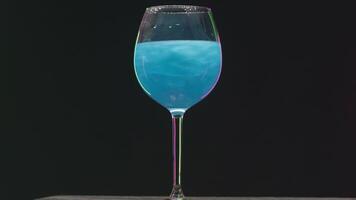 Drink shimmers in a glass on isolated background. Stock footage. Beautiful alcoholic drink with sequins in transparent glass on isolated background. Magic colored drink is poured in glass video