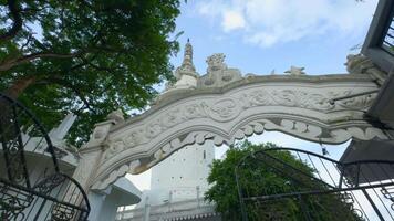 baixo ângulo Visão do uma branco lindo torre e a arco com esculpido elementos em azul nublado céu fundo. Ação. conceito do cultura e arquitetura. video