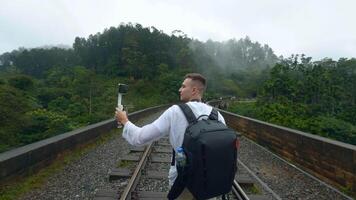 traseiro Visão do uma homem turista levando As fotos do montanha arborizado panorama em Smartphone. Ação. caminhante caminhando em ferrovias. video