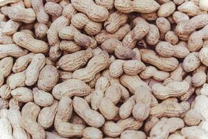 Raw unpeeled groundnuts on brown surface background for food photo
