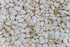 Raw white pumpkin seeds on a white background for healthy snack concepts photo