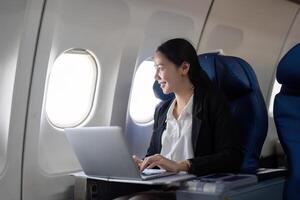 Asian young woman using laptop at first class on airplane during flight, Traveling and Business concept photo