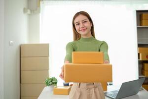 Young business woman asian working online ecommerce shopping at her shop. Young woman sell prepare parcel box of product for deliver to customer. Online selling photo