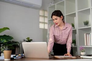 mujer de negocios utilizando ordenador portátil computadora trabajo desde hogar en habitación. Lanza libre, verde habitación área, estilo de vida concepto foto