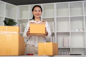 Young woman working online ecommerce shopping at her shop. Young woman sell prepare parcel box of product for deliver to customer. Online selling, ecommerce. Selling products online photo