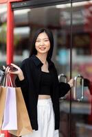 Cheerful Beautiful Asian woman holding shopping bags in shopping in the city on holiday Black Friday photo