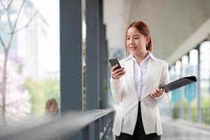 Asian business woman beautiful with smart phone and document file, asian woman with smartphone walking go to work. Preparation for the working day photo