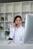 Call center friendly woman asian in office for customer service, technical support and advice, contact and communication with employee operator in help desk agency photo