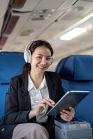 Asian young woman wearing headphone listen to music at first class on airplane during flight, Traveling and Business concept photo