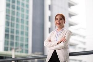 Young happy smiling professional business woman asian, happy confident positive female entrepreneur standing on street arms crossed, looking at camera photo