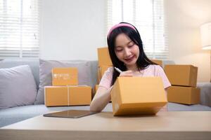 Woman asian in an online store check the customer address and package information on the laptop. Online shopping concept photo