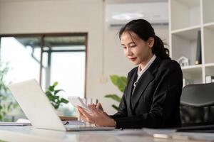 joven negocio mujer asiático o empleado contabilidad teneduría de libros documentos comprobación financiero datos o márketing reporte trabajando en oficina con ordenador portátil. papeleo administración foto