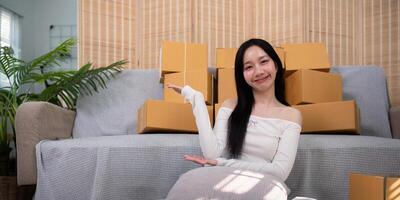 Asian woman small business entrepreneur working from home use tablet for commercial inspection. online marketing Packaging box, concept ecommerce photo