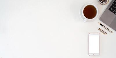 Top view smartphone with empty screen, Laptop and coffee cup on office desk. Copy space for your text photo