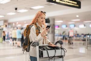 un mujer asiático caminando en un aeropuerto. móvil, maleta y viaje con un joven hembra en un internacional viaje para trabajo o viaje foto