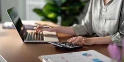 Businesswoman using laptop computer and working at office with calculator document on desk, doing planning analyzing the financial report, business plan investment, finance analysis concept photo