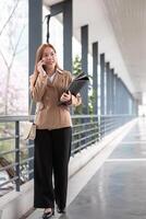 Asian business woman beautiful with smart phone and document file, asian woman with smartphone walking go to work. Preparation for the working day photo