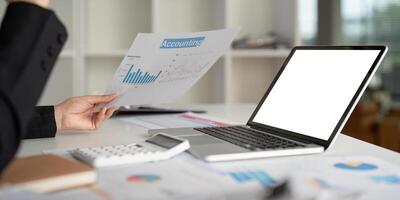 Close up businesswoman using a laptop computer to analysis her financial data. Laptop white screen mockup photo