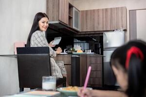 Business woman or mom working with her little daughter at a laptop. Freelance, work from home photo