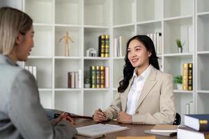 Lawyers woman and businesswoman discussing contract papers sitting at the table. Concepts of law, advice, legal service photo