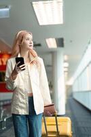 un mujer asiático caminando en un aeropuerto. móvil, maleta y viaje con un joven hembra en un internacional viaje para trabajo o viaje foto