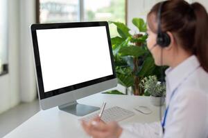 Businesswoman customer support service working with headset and computer with white mockup blank screen at call center photo