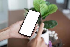 mujer utilizando Bosquejo teléfono inteligente blanco pantalla moderno diseño mientras sentado en el escritorio en hogar foto