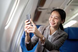 Business woman asian sits in the airplane and using mobile phone while travel or going to work photo