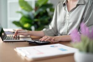 Businesswoman using laptop computer and working at home with calculator document on desk, doing planning analyzing the financial report, business plan investment, finance analysis concept photo