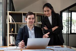 Team business of diverse partner business woman discuss project on laptop sitting at table in office. Two colleague of professional business people working together photo