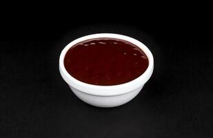 Barbecue sauce in white bowl on black background photo