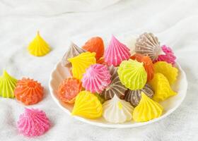 a bowl filled with colorful candy on a white cloth photo