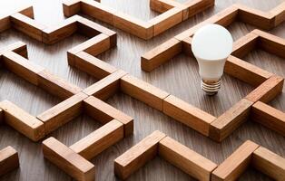 Light bulb in the maze game built by wood blocks, finding the right way to the success, idea concept photo