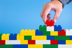 hand building up a wall by stacking up plastic block photo