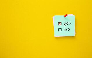 Ticking Yes. Sticky note with red push pin on yellow background. photo