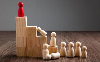 Wooden people figures on top of wooden blocks. Career growth, development and leadership photo