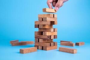 Hand of man piling up and stacking a wooden block. Plan and strategy in business, Risk To Make Business Growth Concept photo