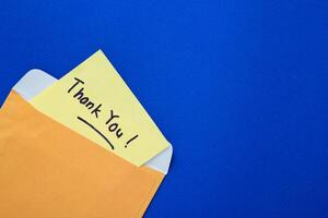 Thank you note on yellow paper in an envelope. photo