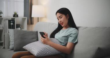 Selective focus ,Happy young woman sitting on sofa enjoy using mobile phone for online shopping cashless in living room at home photo