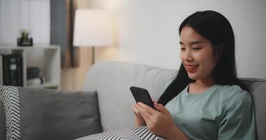 Selective focus ,Happy young woman sitting on sofa enjoy using mobile phone for online shopping cashless in living room at home photo