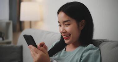 Selective focus ,Happy young woman sitting on sofa enjoy using mobile phone for online shopping cashless in living room at home photo