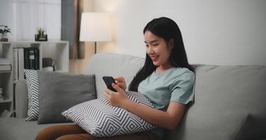 Selective focus ,Happy young woman sitting on sofa enjoy using mobile phone for online shopping cashless in living room at home photo