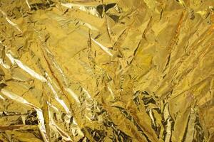 wrinkled golden foil background. texture of golden wrapping paper closeup. photo