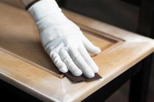 Person remonier worker sands a wooden product, kitchen facade with a sandpaper photo