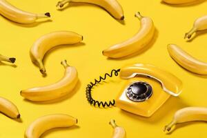 creativo modelo bananas y antiguo amarillo teléfono con difícil oscuridad modelo en amarillo antecedentes plano laico foto