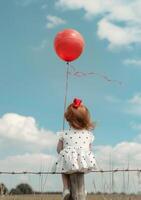 AI generated Little girl is sitting on fence with red balloon photo