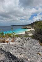 Turquoise waters of a rocky beach under a cloudy sky. photo