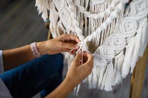 The production of boho-style panels is made of cotton threads of natural color in the macrame photo